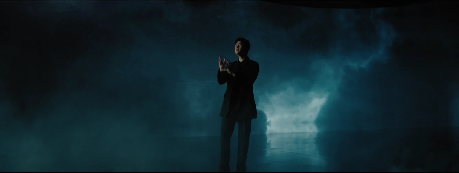 A full-length performance portrait surrounded by deep blue cloud light.