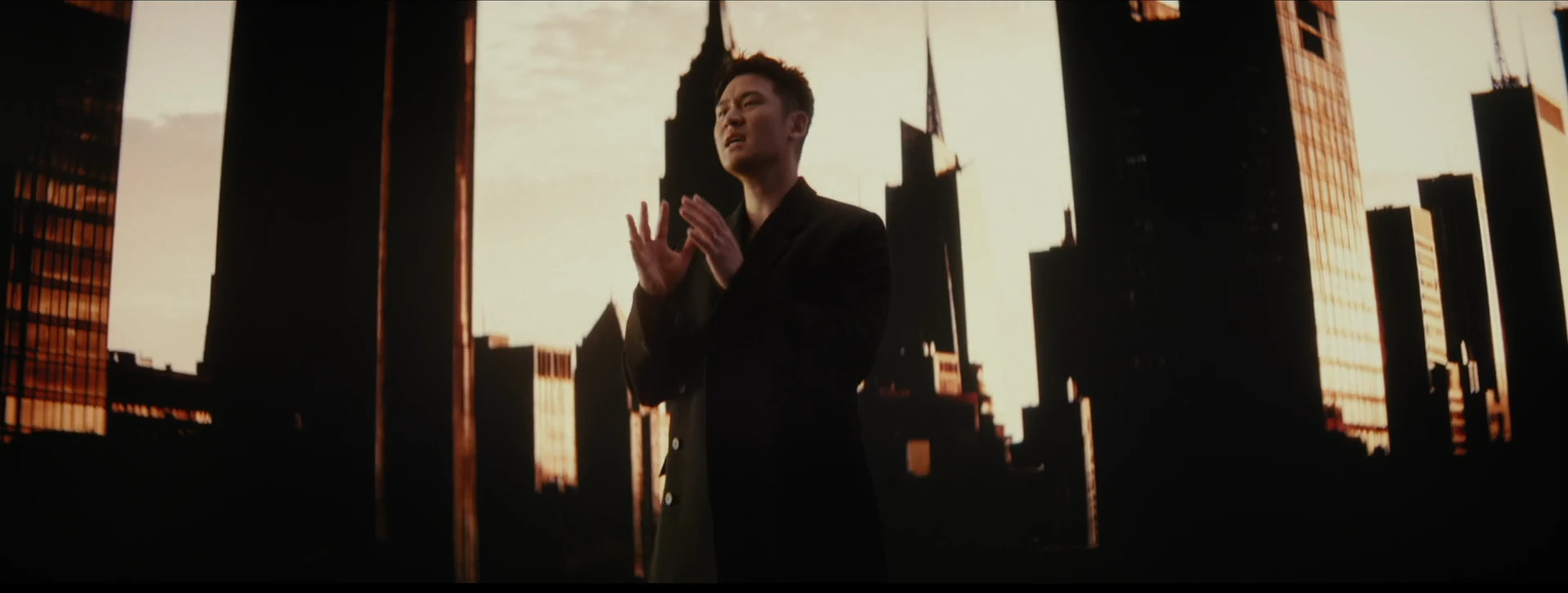 Eric Chou performs with open hands before the golden skyline.