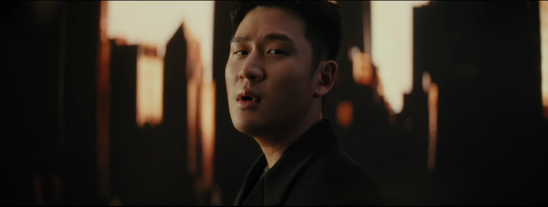 A close portrait of Eric Chou against gold-lit towers.