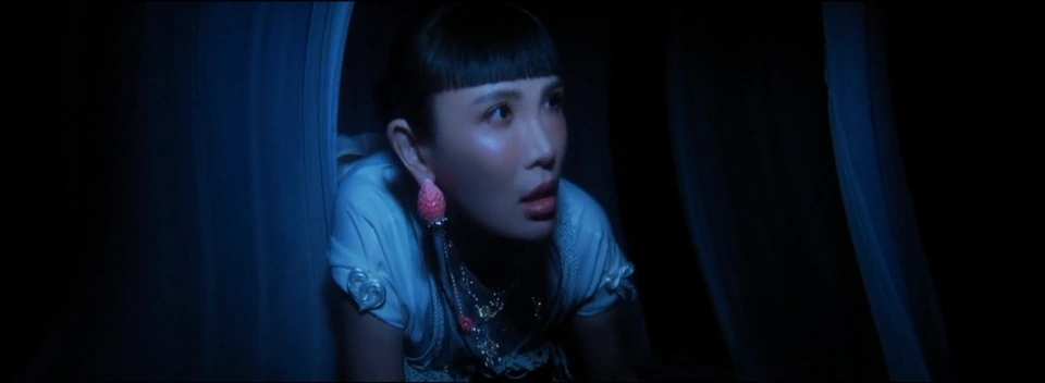 A close view of the performer in blue light, framed by dark curved forms.