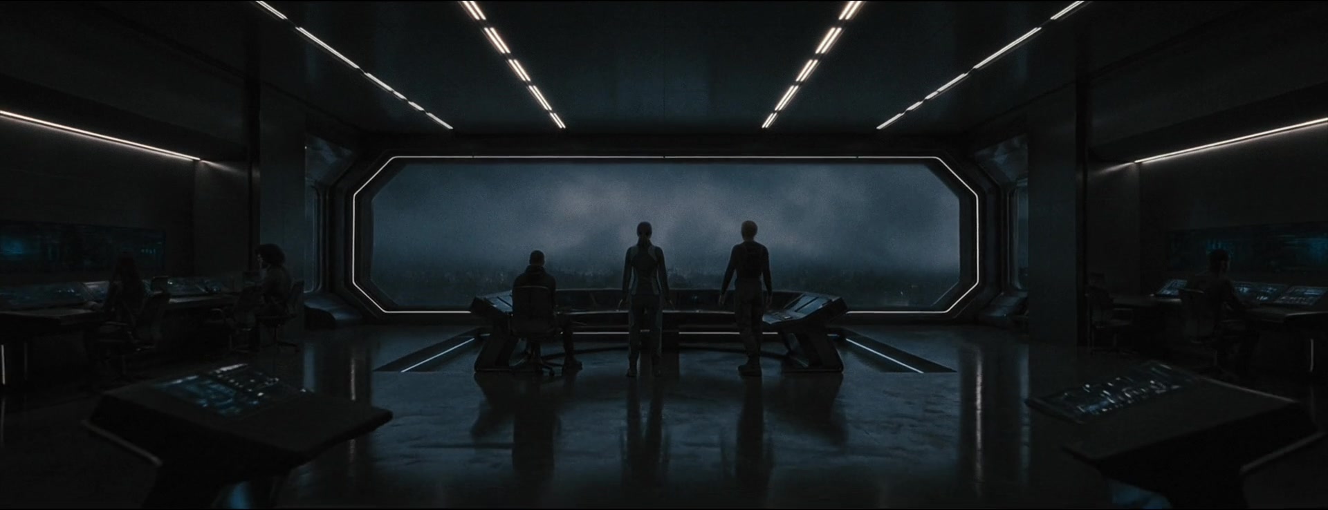 Figures stand at the center of a symmetrical control room facing a vast storm-filled window.