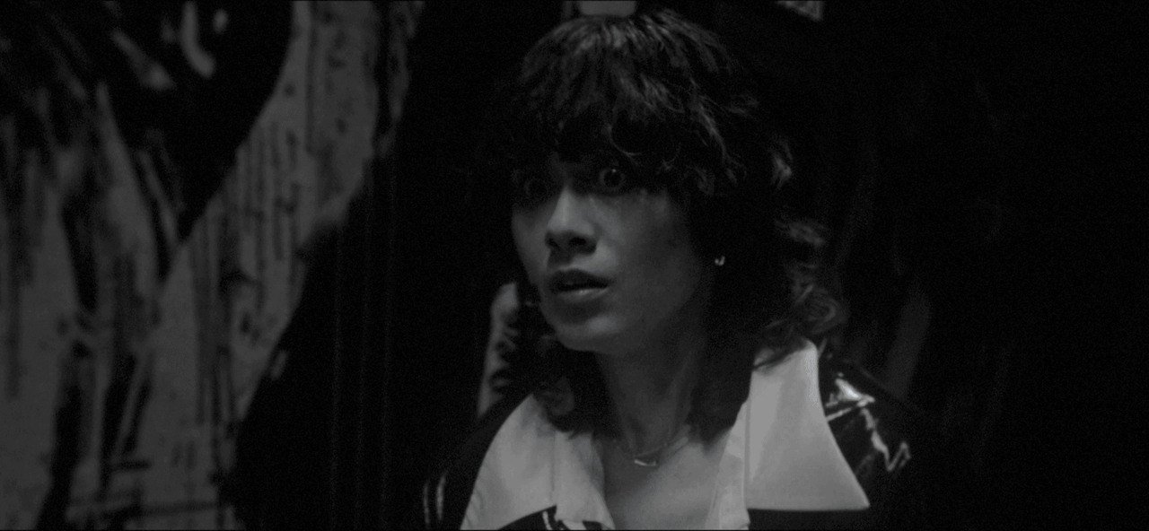 Ghost Swing — The curly-haired protagonist reacts in a monochrome corridor