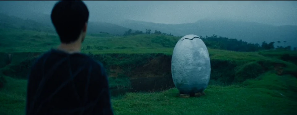 A pale oval stands in the open landscape.
