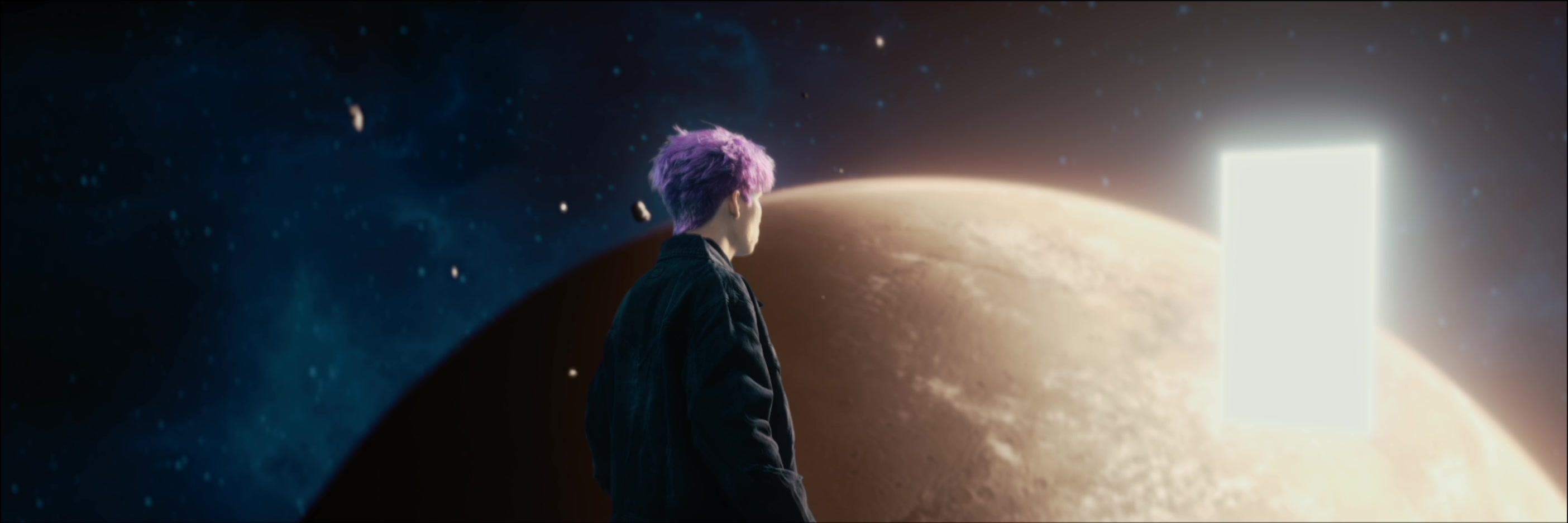 Patrick Brasca faces a bright rectangular portal beside a vast planet.