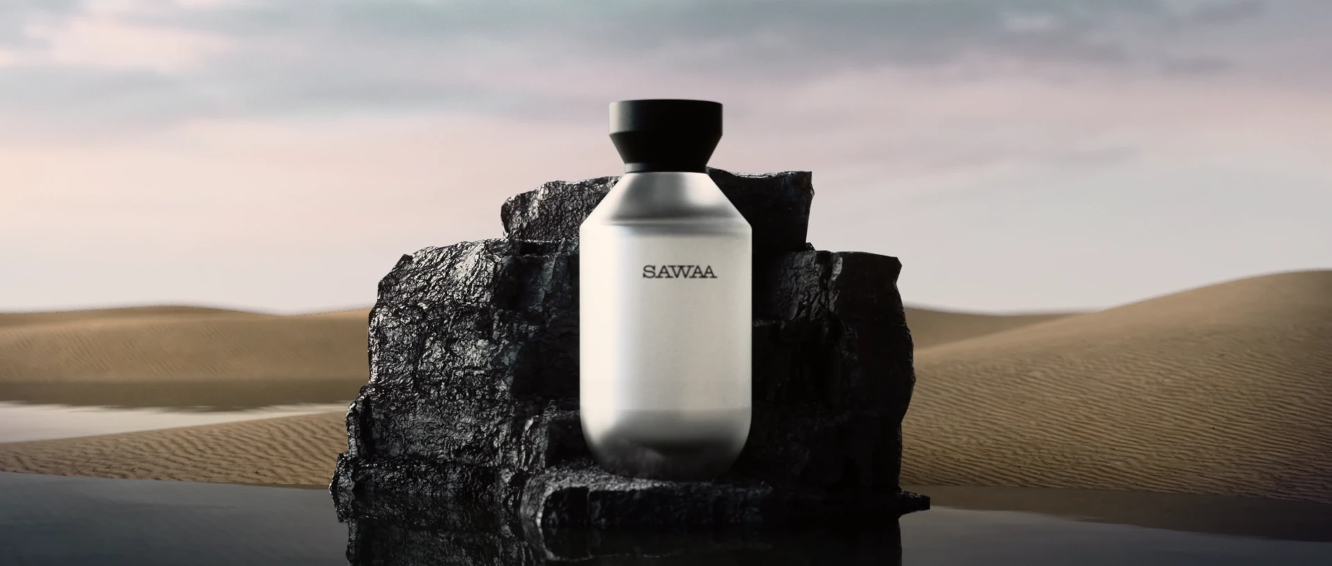 A SAWAA bottle rests on black rock above still water and distant dunes.