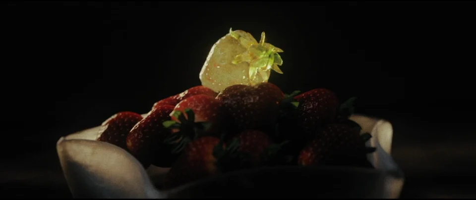 A luminous berry above a bowl of fruit.