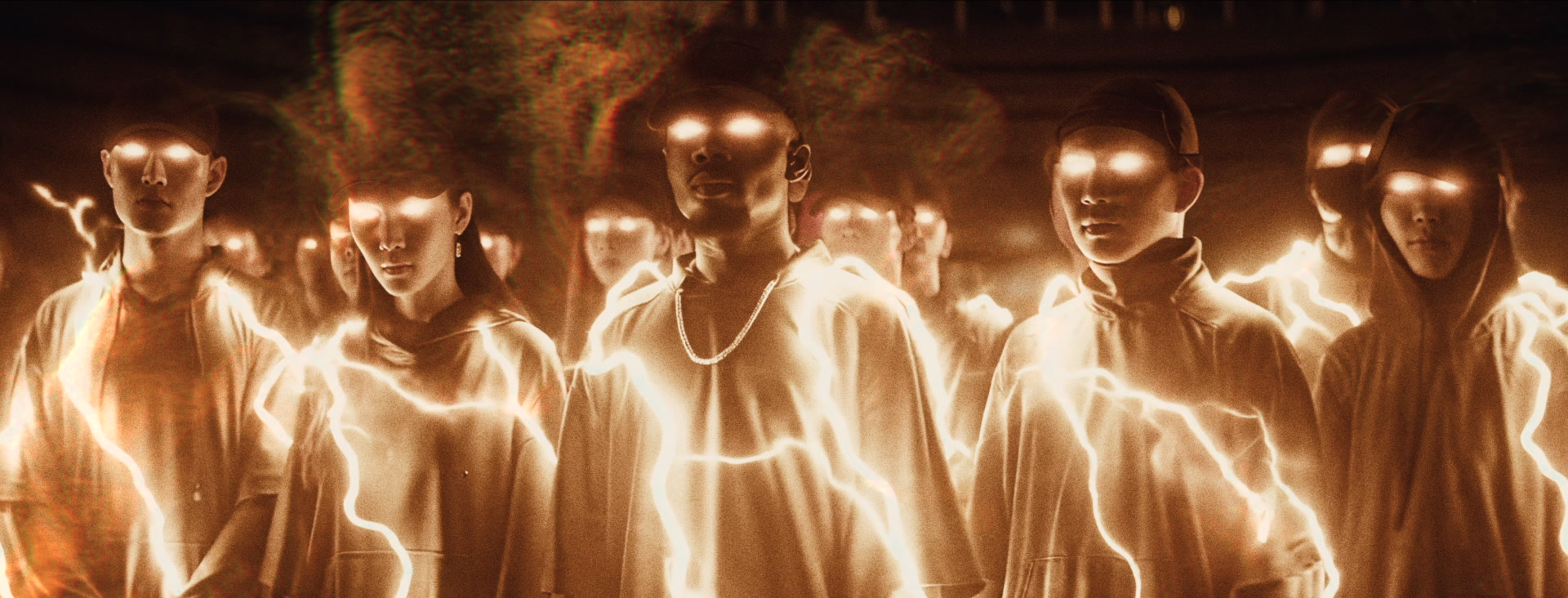 A group of dancers faces the camera with luminous gold outlines and eyes.