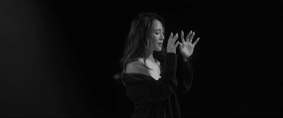 A performer traces hand gestures in monochrome.